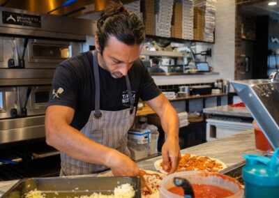 alt=" A pizzamaker from tavola nostra making a pepperoni pizza"