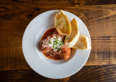 alt=" A plate of Meatballs with tomato sauce and toasted bread on the side"